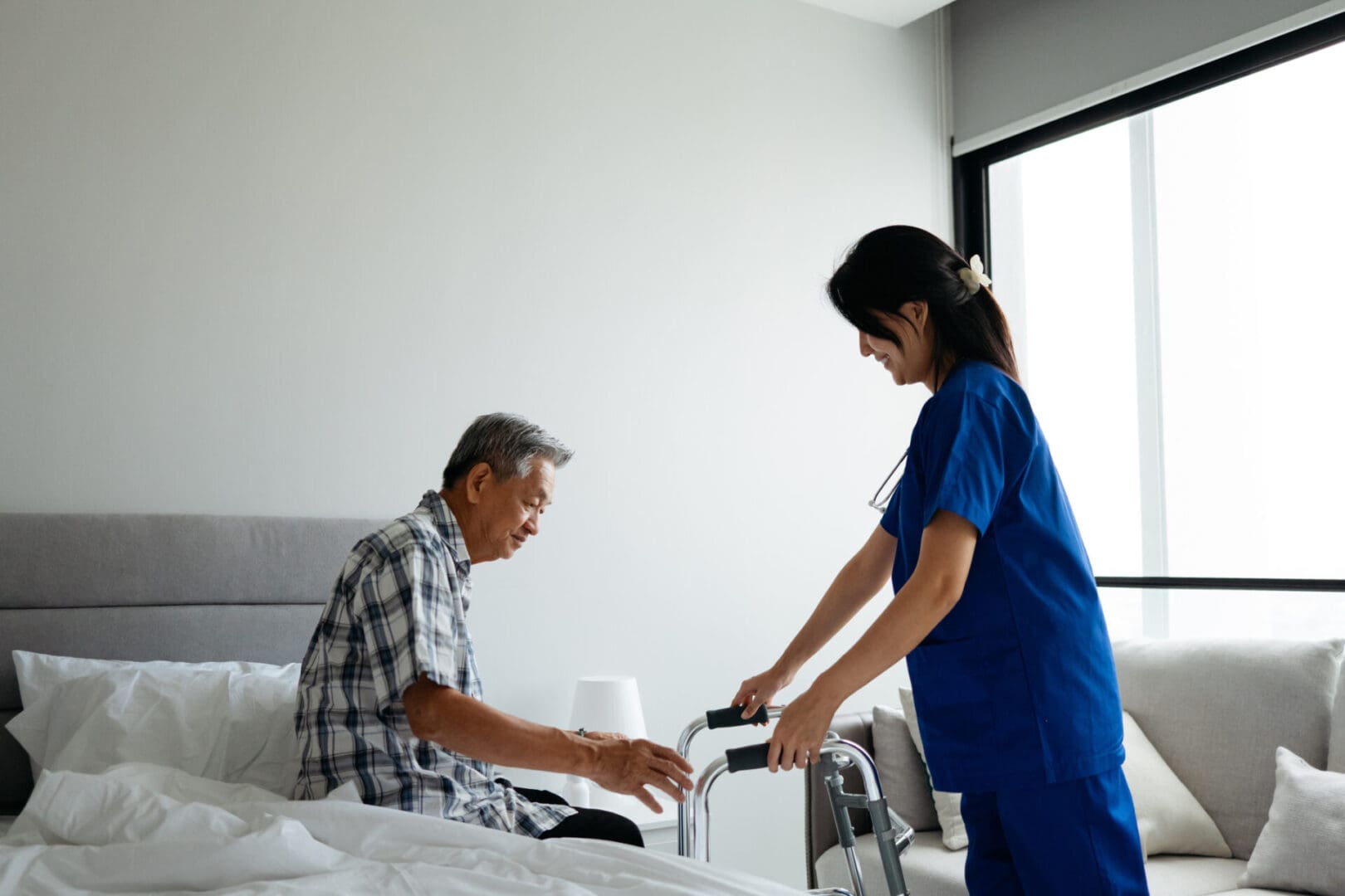 An Asian female healthcare professional supports an elderly man holding a walker, highlighting patient rehabilitation, senior independence, and compassionate elderly care.